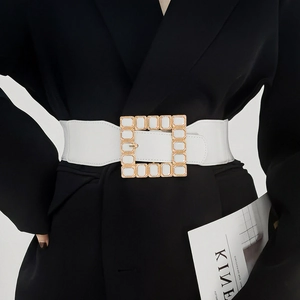 Close-up of a wide white elastic waist belt with a square gold buckle and white gemstones