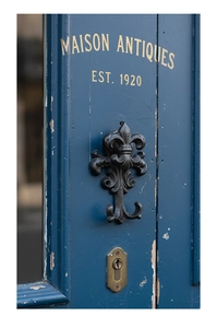 Detail of vintage cast iron fleur-de-lis wall hook on rustic blue wooden background