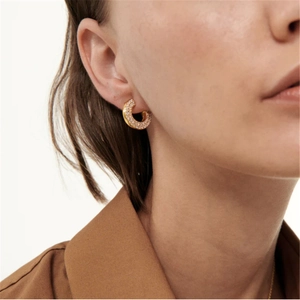 Side view of C-shaped gold hoop earrings featuring micro-paved rhinestones on a model