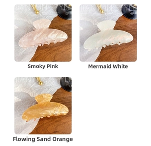 Detailed view of iridescent acrylic hair claws in pearl pink, white and orange