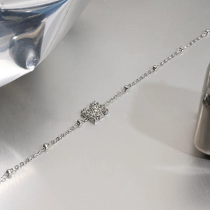 Macro detail of silver titanium bracelet featuring a letter M pendant with paved zircons
