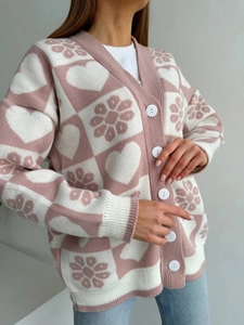 Détail du cardigan en maille à carreaux rose et blanc avec motifs de cœurs et boutons blancs