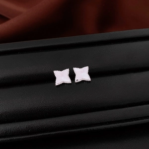 Macro view of silver star stud earrings with beaded edges and radial texture detail