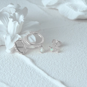 Detailed view of silver opal earrings set with sparkling stones on a white textured surface