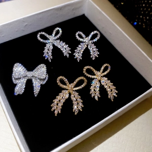 Detailed view of silver and gold bowknot earrings and brooch set with sparkling cubic zirconia