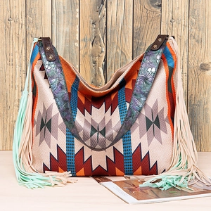 Detail of bohemian shoulder bag with ethnic geometric patterns and fringe accents
