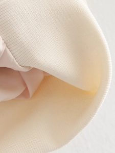 Gros plan détaillé des poignets côtelés et de la doublure rose du blouson aviateur beige