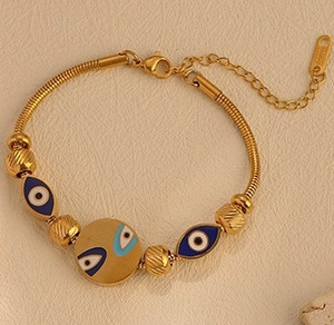 Close-up of golden Evil Eye snake chain bracelet with blue enamel charms and lobster clasp