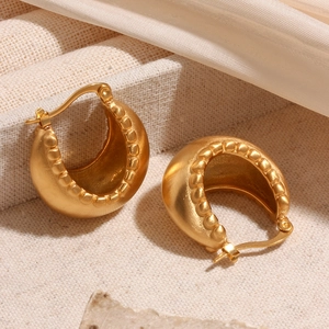Detail of 18K gold-plated C-shaped earrings with brushed texture and beaded edges on marble