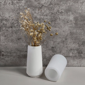 Minimalist white cylindrical resin mold with dried flowers on concrete background