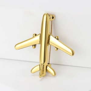 Detail showing the golden metal airplane brooch with a minimalist vintage design and pin