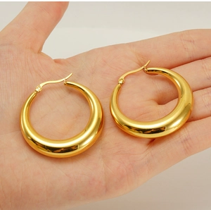 Handheld view of chunky gold teardrop hoop earrings showing size and polished finish