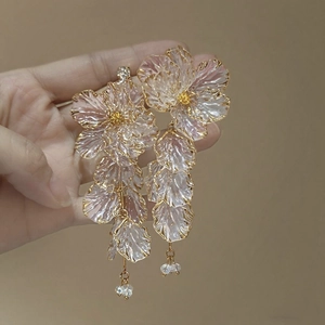 Detailed macro of pink acrylic flower petals with gold edges and long tassel earrings