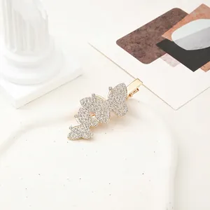 Close-up of golden butterfly hair clip with sparkling rhinestones and duckbill clamp