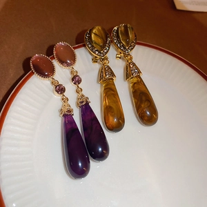 Detailed view of vintage resin teardrop earrings in purple and amber colors