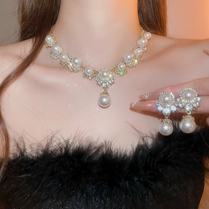 Detailed view of luxury gold necklace and earrings set with white pearls and rhinestones
