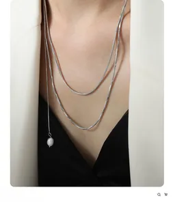 Close-up of a double-layered silver snake chain with a white baroque pearl pendant