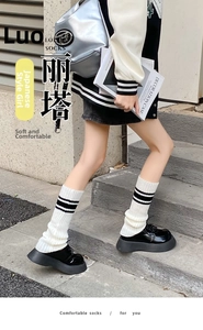 Detail view of white knitted leg warmers with black stripes and Y2K school style
