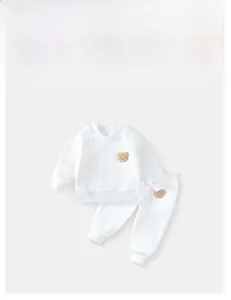 Flat lay of white children fleece set featuring cute brown plush bear patches on fabric