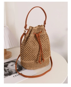 Detail of hollow straw bucket bag featuring dark brown leather drawstring and metal rings