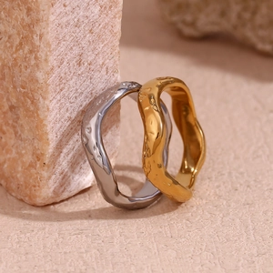Gold and silver stainless steel rings with hammered texture resting on a beige stone