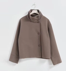 Détail de la veste marron à col montant avec fermeture boutonnée latérale et maille dense