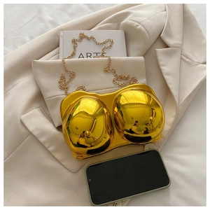 Artistic gold female bust shaped evening bag with chain strap on beige suit fabric