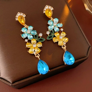 Close-up of vintage gold floral earrings with blue and yellow rhinestone tassels