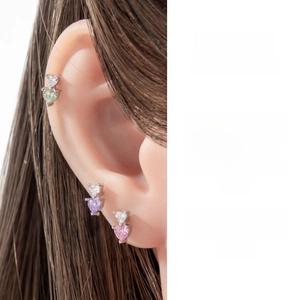 Detailed view of three heart-shaped zircon cartilage studs in green, purple, and pink