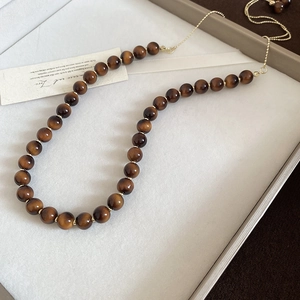 Macro detail of tiger eye stone beads with gold spacers on an elegant necklace chain