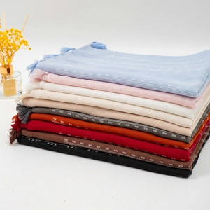 Detail of neatly folded linen scarves with fringe edges and subtle textured patterns