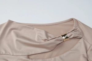 Détail du col de robe champagne avec boucle dorée et texture élégante de tissu plissé fin