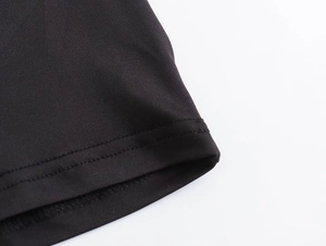 Close-up of black nylon dress showing high-quality double-needle stitching and knit texture