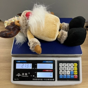 Christmas gnome doll with reindeer hat being weighed on a scale to show its weight