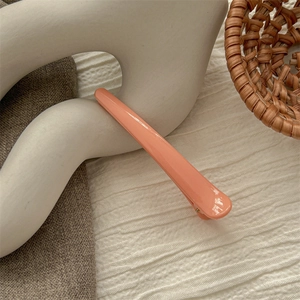 Macro detail of glossy coral pink seamless hair clip on elegant neutral fabric