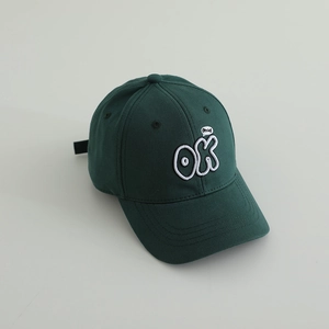 Detailed close-up of white OK letter embroidery on a dark green cotton baseball cap