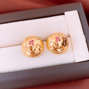 Macro shot of gold-plated vintage round earrings with floral engraving and pink stones