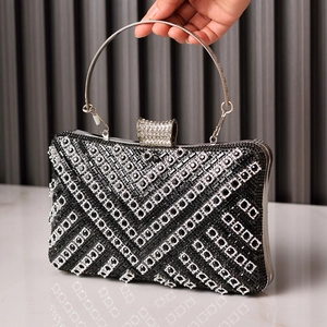 Elegant black evening clutch with sparkling rhinestones and metal handle held by hand
