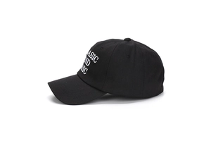 Gros plan détaillé de la broderie blanche BASIC AND BASIC sur une casquette en coton noir