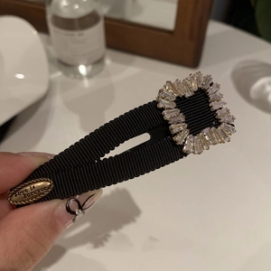 Detail of Y2K black rhinestone hair clip with Love is Forever engraved metal plate