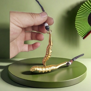 Porte-clés ver à soie doré avec cordon tressé et perles sur support d'exposition vert