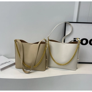 Detail of beige and white chain shoulder bags on a minimalist white table background