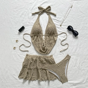 Detailliertes Flatlay eines beigen dreiteiligen Bikini-Sets mit Plissee-Textur und Accessoires