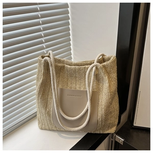 Detailansicht der beigen Strohtasche mit dicken Seilgriffen und modischem PU-Lederaufnäher