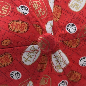 Détail de la calotte d'une casquette en coton rouge avec broderie de caractères chinois dorés
