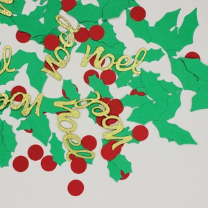 Close-up of Noel gold glitter confetti with green holly leaves and red dot decorations