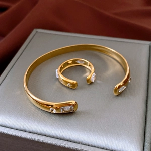 Detail view of gold stainless steel bangle and ring set with cubic zirconia on silk