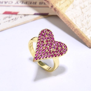 Macro shot of gold-plated heart ring featuring pink cubic zirconia on a white table