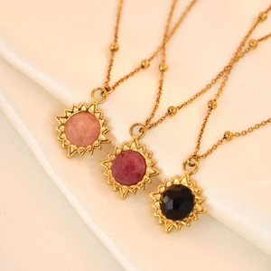 Golden sun pendant necklaces with colorful faceted stones on soft silk fabric