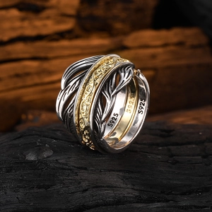 Macro detail of multi-layer feather ring with S925 engraving on dark charcoal base